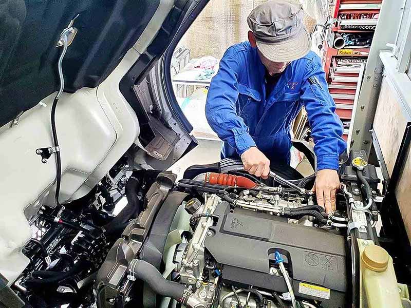 トラックのエンジンルームを整備する様子