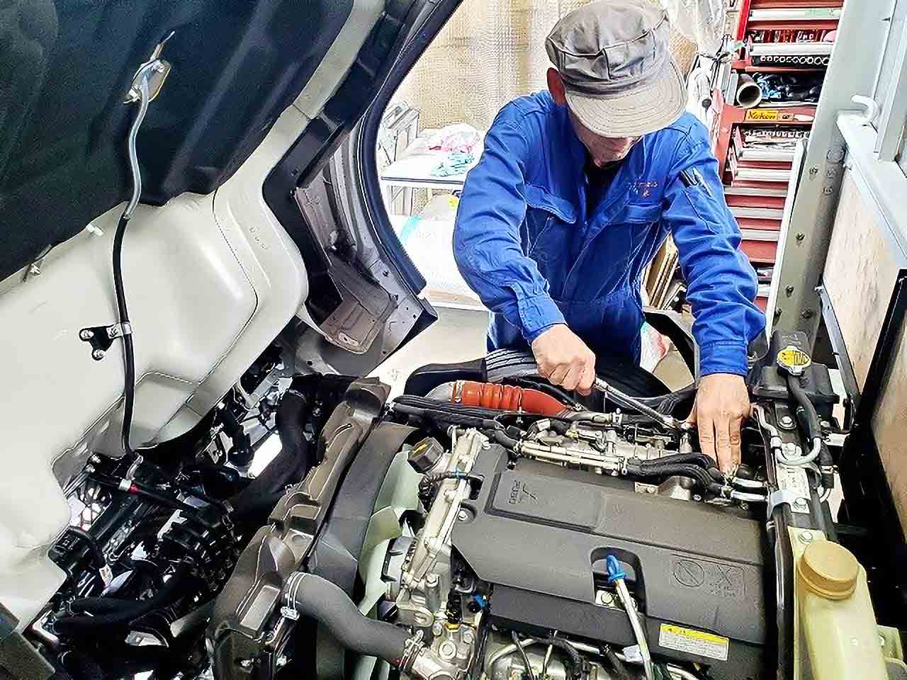 トラックのエンジンルームを整備する様子